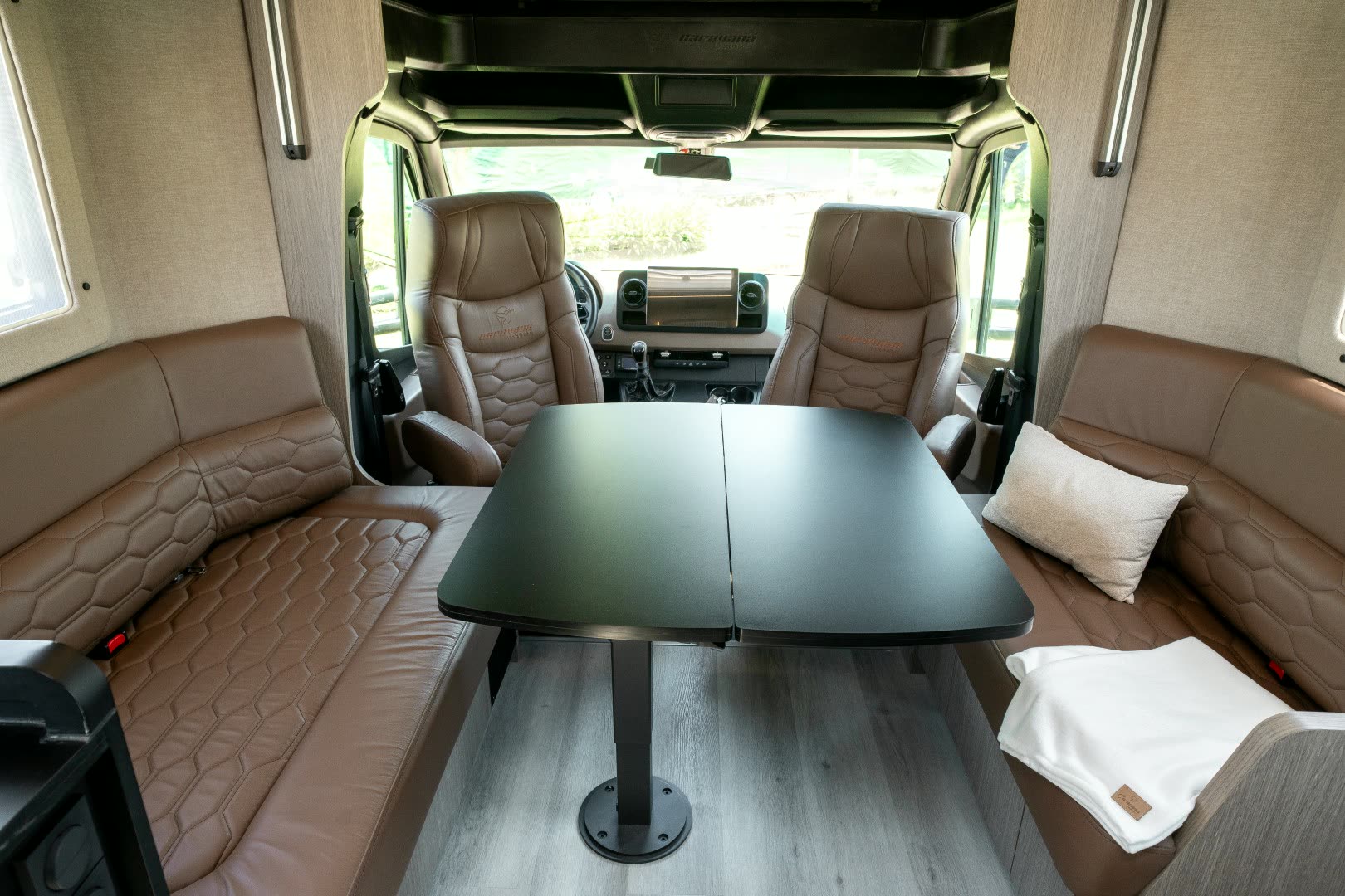 Dinette en cuero caramelo y madera dentro de un motorhome Caravana